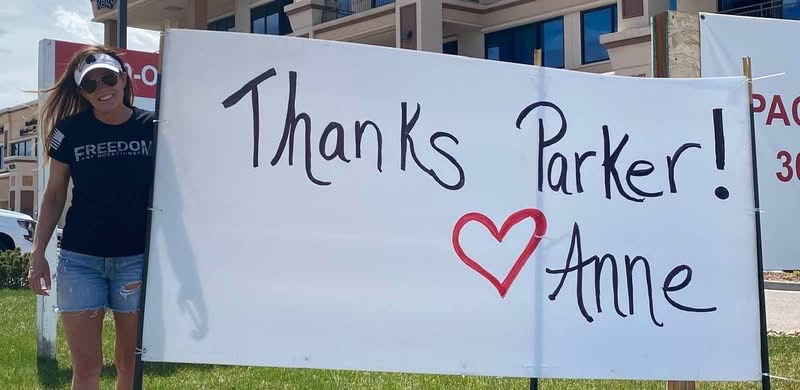 Anne Barrington standing beside a hand-lettered Thanks Parker! banner